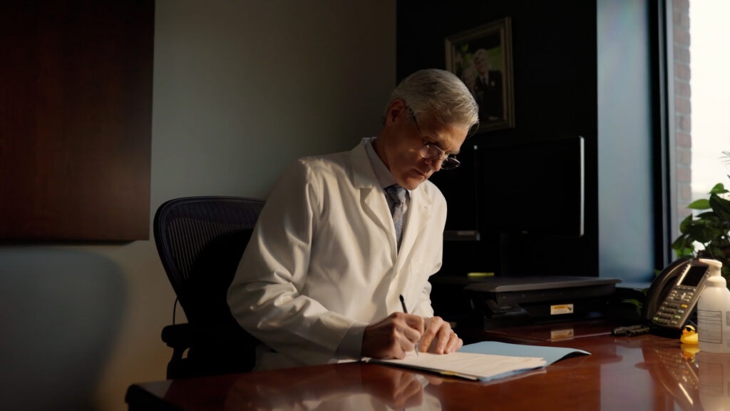 Dr. Robert R. Mayo at his desk, writing on a sheet of paper.