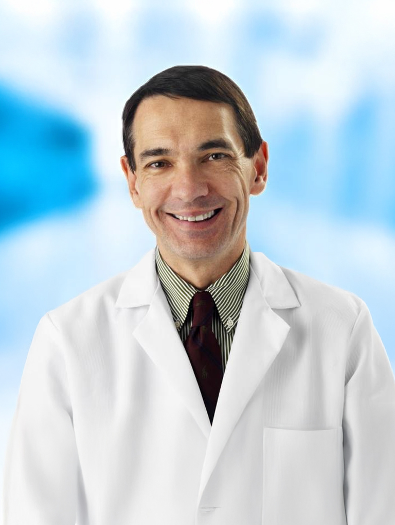 Dr. Gerald V. Maloney in a lab coat.