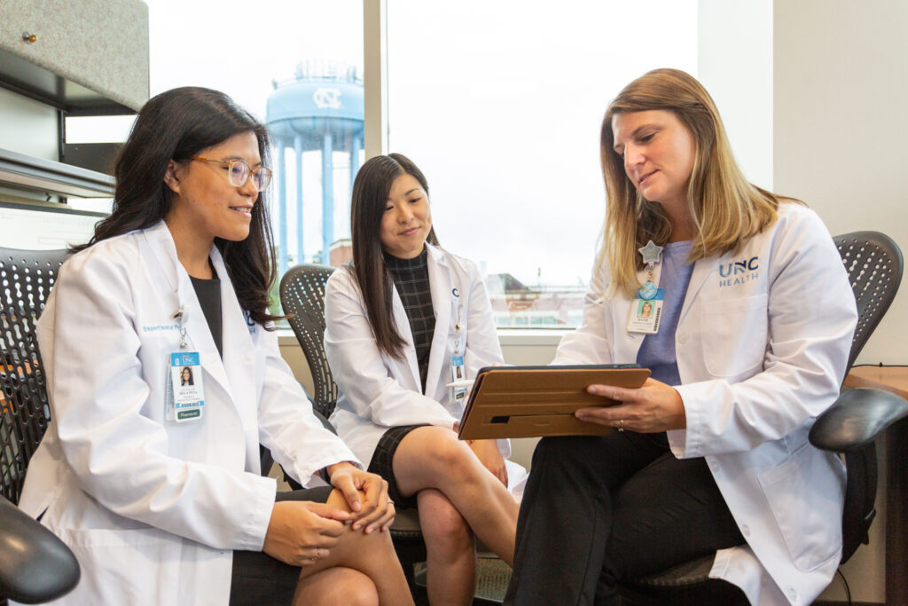 three female pharmacist meeting and going over information on a tablet