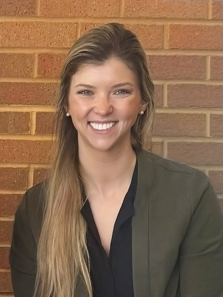 Courtney Wulffson in front of a brick background.
