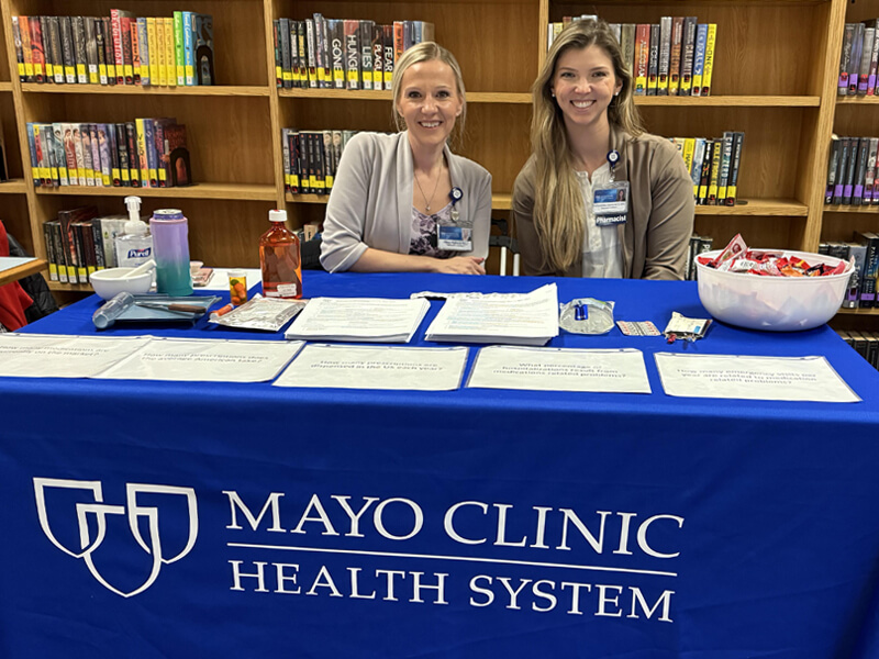 Courtney Wulffson with a colleague seated at a table with Mayo Clinic Health System logo on the tablecloth.