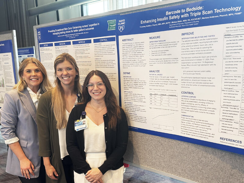 Courtney Wulffson with a colleagues standing next to a poster presentation.